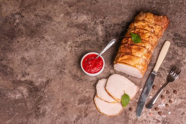 Taş bir arka planda dilimlenmiş domuz filetosu. Modaya uygun sert bir ışık, karanlık bir gölge, baharatlar ve otlar, üst manzara.