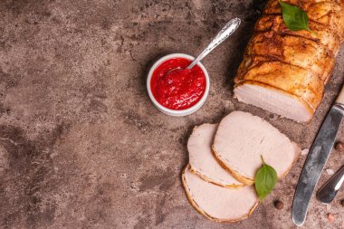 Taş bir arka planda dilimlenmiş domuz filetosu. Modaya uygun sert bir ışık, karanlık bir gölge, baharatlar ve otlar, üst manzara.