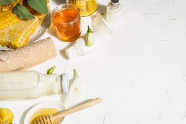 Ballı ve sütlü spa konsepti. Doğal kozmetikler, organik malzemeler. Sert ışık, karanlık gölge. Beyaz macun arkaplan, üst görünüm