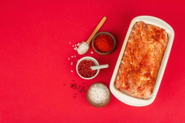 Kırmızı bir arka planda pişmeye hazır domuz filetosu turşusu. Kokulu baharatlar, sağlıklı yemek pişirmek için kullanışlı malzemeler.