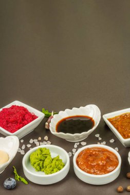 Farklı soslar - ketçap, mayonez, barbekü, soya, turşu, wasabi, adjika, yaban turpu, aioli, marinara. Koyu taş beton arka plan, kapat