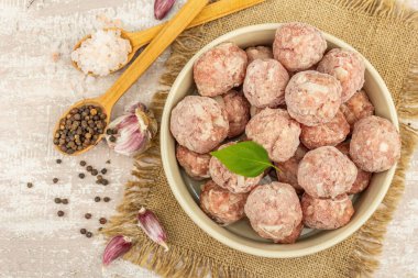 Baharatlı donmuş köfte, fesleğen yaprağı ve seramik kasede sarımsak karanfili. Yemek pişirmek için ham malzemeler. Ahşap arkaplan, üst manzara