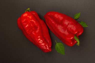 Siyah taş arka planda izole edilmiş dev kırmızı dolma biber. Tatlı sebze, yeni hasat, sağlıklı yiyecekler için taze malzeme. Koyu renk duvar kâğıdı, üst manzara.