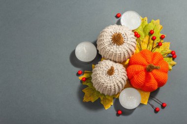 Örülmüş balkabakları, mumlar, yapraklar ve geleneksel dekorlarla sonbahar kompozisyonu. Modaya uygun sert ışık, karanlık gölge. Gri mat arkaplan, üst görünüm