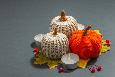 Örülmüş balkabakları, mumlar, yapraklar ve geleneksel dekorlarla sonbahar kompozisyonu. Modaya uygun sert ışık, karanlık gölge. Gri mat arkaplanı, kopyalama alanı