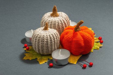 Örülmüş balkabakları, mumlar, yapraklar ve geleneksel dekorlarla sonbahar kompozisyonu. Modaya uygun sert ışık, karanlık gölge. Gri mat arkaplanı, kapat