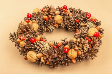 Sonbahar koni, fıstık ve böğürtlen çelengi. Yaratıcı kompozisyon, el yapımı. Ev dekorasyonu festivali konsepti. Açık bej arkaplan, kapat