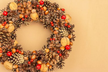 Sonbahar koni, fıstık ve böğürtlen çelengi. Yaratıcı kompozisyon, el yapımı. Ev dekorasyonu festivali konsepti. Açık bej arkaplan, üst görünüm