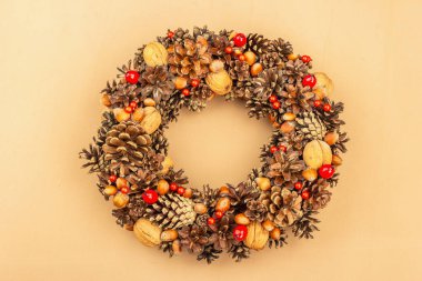 Sonbahar koni, fıstık ve böğürtlen çelengi. Yaratıcı kompozisyon, el yapımı. Ev dekorasyonu festivali konsepti. Açık bej arkaplan, üst görünüm