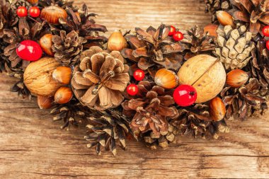 Sonbahar koni, fıstık ve böğürtlen çelengi. Yaratıcı kompozisyon, el yapımı. Ev dekorasyonu, şenlik konsepti, eski ahşap arka plan, kapat.