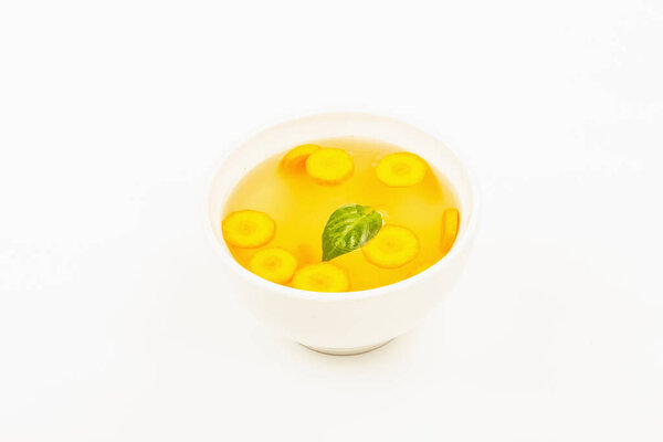 Transparent chicken broth in a ceramic bowl isolated on white background. Traditional bouillon, healthy food, ripe vegetables