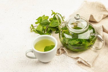Hafif arka planda mis kokulu nane çayı. Cam çaydanlık, bir fincan çay, bir demet taze nane. Günaydın konsept, kopyalama alanı