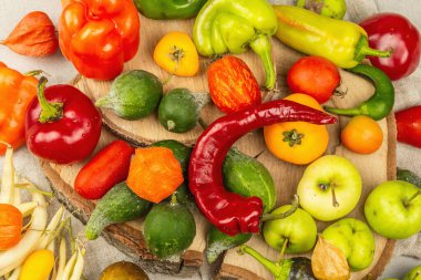 Modaya uygun çirkin sebzeler ve meyveler. Taze biber, fasulye, salatalık, domates, balkabağı, elma çeşitleri. Organik çirkin yemekler pişirmek. Taş beton zemin, üst görünüm