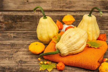 Sonbahar tarzı kompozisyon. Olgun balkabakları, sıcak örülmüş süveter, sonbahar yaprakları ve böğürtlen. Şükran Günü ya da Cadılar Bayramı keyfi. Eski tahta arkaplan