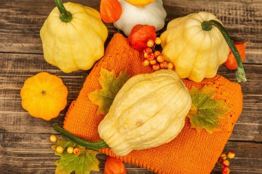 Sonbahar tarzı kompozisyon. Olgun balkabakları, sıcak örülmüş süveter, sonbahar yaprakları ve böğürtlen. Şükran Günü ya da Cadılar Bayramı keyfi. Eski ahşap zemin, üst manzara