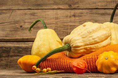 Sonbahar tarzı kompozisyon. Olgun balkabakları, sıcak örülmüş süveter, sonbahar yaprakları ve böğürtlen. Şükran Günü ya da Cadılar Bayramı keyfi. Eski tahta arkaplan