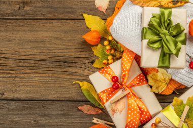 Sonbahar tasarımlı sıfır atık hediye konsepti. Sıcak kazaklar, dökülen yapraklar, tematik dekorasyon. Yumuşak ışık, eski tahta arka plan, üst manzara