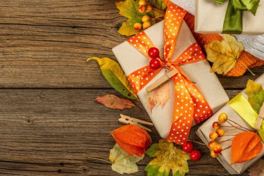 Sonbahar tasarımlı sıfır atık hediye konsepti. Sıcak kazaklar, dökülen yapraklar, tematik dekorasyon. Yumuşak ışık, eski tahta arka plan, üst manzara
