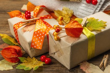 Sonbahar tasarımlı sıfır atık hediye konsepti. Sıcak kazaklar, dökülen yapraklar, tematik dekorasyon. Yumuşak ışık, eski tahta arka plan, kapat