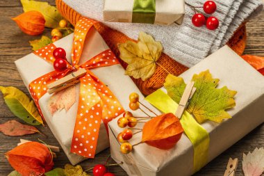 Sonbahar tasarımlı sıfır atık hediye konsepti. Sıcak kazaklar, dökülen yapraklar, tematik dekorasyon. Yumuşak ışık, eski tahta arka plan, kapat
