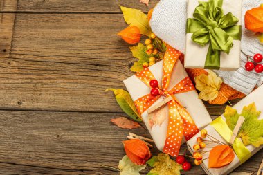 Sonbahar tasarımlı sıfır atık hediye konsepti. Sıcak kazaklar, dökülen yapraklar, tematik dekorasyon. Yumuşak ışık, eski tahta arka plan, üst manzara