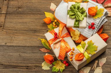 Sonbahar tasarımlı sıfır atık hediye konsepti. Sıcak kazaklar, dökülen yapraklar, tematik dekorasyon. Yumuşak ışık, eski tahta arka plan, üst manzara