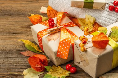 Sonbahar tasarımlı sıfır atık hediye konsepti. Sıcak kazaklar, dökülen yapraklar, tematik dekorasyon. Yumuşak ışık, eski tahta arka plan, boşluğu kopyala