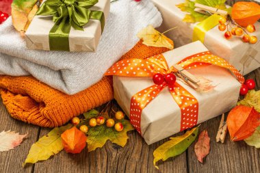 Sonbahar tasarımlı sıfır atık hediye konsepti. Sıcak kazaklar, dökülen yapraklar, tematik dekorasyon. Yumuşak ışık, eski tahta arka plan, kapat