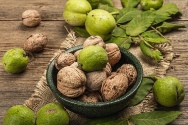 Olgun kahverengi ve olgunlaşmamış yeşil cevizler bir kasede. Eski ahşap arka plan, kapat