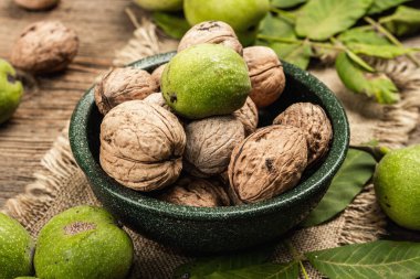 Olgun kahverengi ve olgunlaşmamış yeşil cevizler bir kasede. Eski ahşap arka plan, kapat