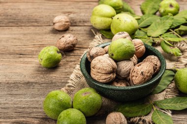 Olgun kahverengi ve olgunlaşmamış yeşil cevizler bir kasede. Eski tahta arkaplan, kopyalama alanı