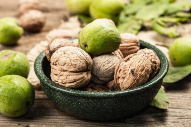 Olgun kahverengi ve olgunlaşmamış yeşil cevizler bir kasede. Eski ahşap arka plan, kapat