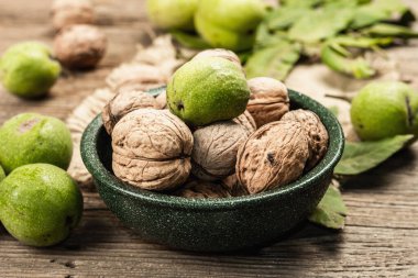 Olgun kahverengi ve olgunlaşmamış yeşil cevizler bir kasede. Eski ahşap arka plan, kapat