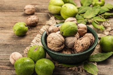 Olgun kahverengi ve olgunlaşmamış yeşil cevizler bir kasede. Eski ahşap arka plan, kapat