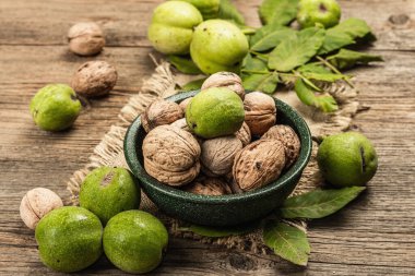 Olgun kahverengi ve olgunlaşmamış yeşil cevizler bir kasede. Eski ahşap arka plan, kapat