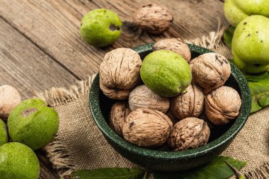 Olgun kahverengi ve olgunlaşmamış yeşil cevizler bir kasede. Eski tahta arkaplan, kopyalama alanı