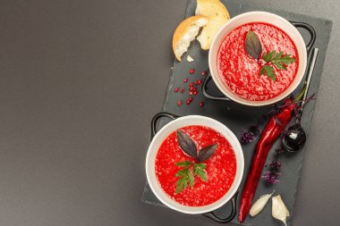 Baharatlı sonbahar domates çorbası. Sağlıklı sıcak yemek, sarımsak, biber, fesleğen. Siyah taş arkaplan, üst görünüm