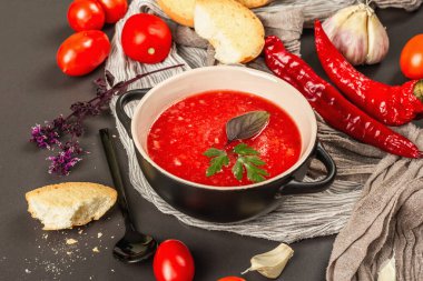 Vejetaryen yemeği, baharatlı domates çorbası, kızarmış ekmek, olgun sebzeler ve taze fesleğen otu. Siyah taş beton arka plan, kapat