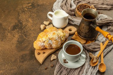 Kahve ve kruvasan, günaydın ve kahvaltı konsepti. Kahveli bakır Türk, sütlü sürahi, kahve çekirdekleri. Kahverengi taş arkaplan, kopyalama alanı