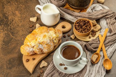 Kahve ve kruvasan, günaydın ve kahvaltı konsepti. Kahveli bakır Türk, sütlü sürahi, kahve çekirdekleri. Kahverengi taş arkaplan, kopyalama alanı