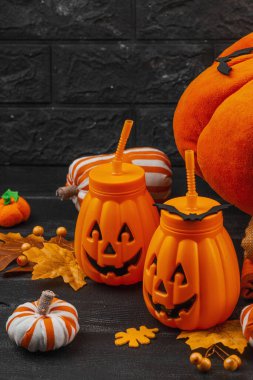 El yapımı balkabakları, yumuşak yastıklar ve balkabağı şeklindeki içecek bardaklarıyla Cadılar Bayramı süslemesi. Konforlu mevsimlik kurulum güz geleneklerini ve festival sanatlarını sembolize ediyor, kopyalama alanı