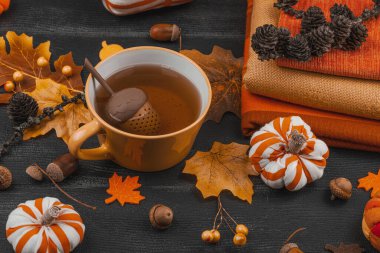 Bir fincan çay, el yapımı kumaş balkabakları, meşe palamutları, kozalakları, dökülen yapraklar ve zanaatlar için tekstil, yavaş yaşam ve mevsimsel konforu sembolize eden,