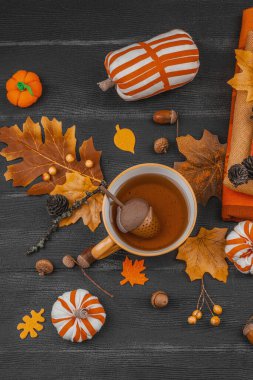 Bir fincan çay, el yapımı kumaş balkabakları, meşe palamutları, kozalakları, dökülen yapraklar ve zanaatlar için tekstil, yavaş yaşam ve mevsimsel konforu sembolize eden,