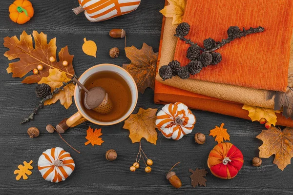 Bir fincan çay, el yapımı kumaş balkabakları, meşe palamutları, kozalakları, dökülen yapraklar ve zanaatlar için tekstil, yavaş yaşam ve mevsimsel konforu sembolize eden,