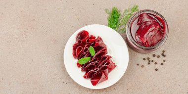 Cam bir kavanozda ve tabakta fermente pancar dilimleri. Ev yapımı, probiyotik zengini, vejetaryen ve mide sağlığı için sağlıklı beslenme. Açık kahverengi arkaplan, pankart biçimi