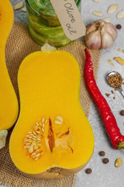 Zeytin yağı, deniz tuzu, biber ve kırmızı biberli yarım tereyağlı kabak. Vejetaryen sağlıklı beslenme, sonbahar hasadı, çiftlikten sofraya yemek pişirme, hafif taş arka plan, üst manzara.