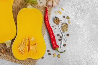 Zeytin yağı, deniz tuzu, biber ve kırmızı biberli yarım tereyağlı kabak. Vejetaryen sağlıklı beslenme, sonbahar hasadı, çiftlikten sofraya yemek pişirme, hafif taş arka plan, üst manzara.