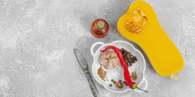 Zeytin yağı, deniz tuzu, biber ve kırmızı biberli yarım tereyağlı kabak. Vejetaryen sağlıklı beslenme, sonbahar hasadı, çiftlikten sofraya yemek pişirme, hafif taş arka plan, afiş biçimi