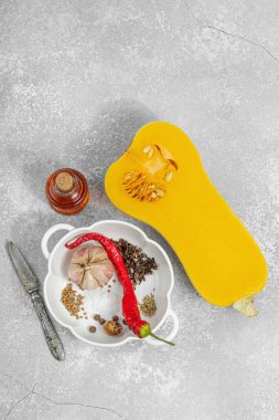 Zeytin yağı, deniz tuzu, biber ve kırmızı biberli yarım tereyağlı kabak. Vejetaryen sağlıklı beslenme, sonbahar hasadı, çiftlikten sofraya yemek pişirme, hafif taş arka plan, üst manzara.