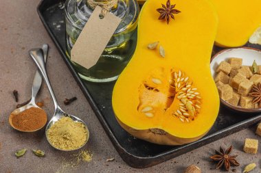 Koyu bir tepside yarım tereyağlı ezme ve içinde pişirme malzemeleri var. Esmer şeker, tarçın çubukları, zencefil, hindistan cevizi. Geleneksel sonbahar turtası ve tatlı tarifleri için baharatlar, sıcak kahverengi arka plan, yakın çekim.